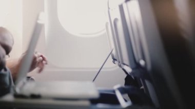 Yakın çekim yan görünüm uçak yolcularının uçuş sırasında çeşitli mobil cihazlar, akıllı telefonlar ve dokunmatik ekran dizüstü kullanarak.