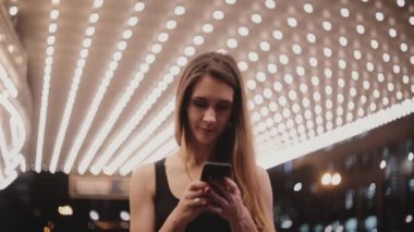 Mutlu güzel yerel kadın eğlence akşamı gülümseyen messenger kullanarak smartphone bakarak şaşırtıcı Chicago tiyatro.