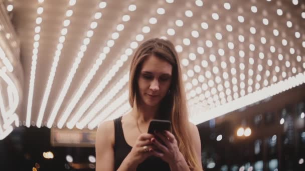 Ευτυχής όμορφη γυναίκα τοπικά στον εκπληκτικό Σικάγου θεάτρου βλέπουν smartphone χρησιμοποιώντας το messenger χαμογελώντας ελεύθερου χρόνου το βράδυ. — Αρχείο Βίντεο