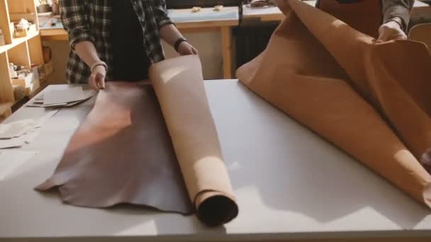 Vue grand angle homme et femme travaillant ensemble dans un atelier de fabrication léger avec de gros morceaux de cuir sur une table . — Video