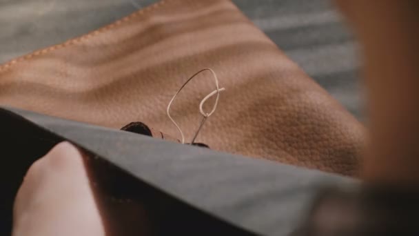 Крупный план женских рук, шьющих вручную грубую кожаную сумку с иглами, процесс изготовления качественной продукции — стоковое видео