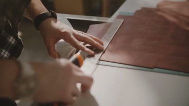 Bıçak ve eğri cetvel ile hafif atölye tabloda büyük deri parça kesme eller güzel yakın çekim çekim.