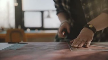 Bıçak ve eğri cetvel ile atölye tabloda da yetenekli kadın esnaf kesim büyük deri parçasının güzel yakın çekim shot