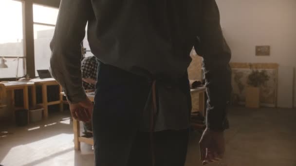 Artisanat masculin entrant dans l'atelier de fabrication, artisan coupant le cuir en morceaux pour les marchandises faites à la main au ralenti 