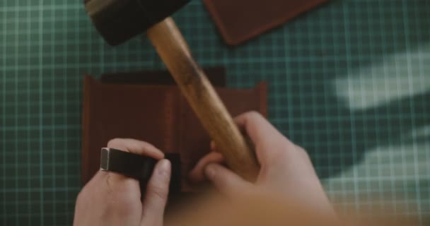 特写镜头的顶部拍摄专业女性手在小一块皮革与锤子和冲床的孔. — 图库视频影像