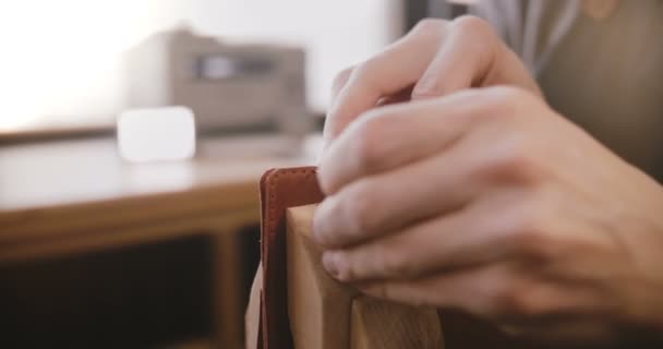 Nahaufnahme männlicher Hände beim Nähen handgefertigter Lederwaren auf Sattler mit Nadeln in Co-Working Manufacturing-Werkstatt. — Stockvideo