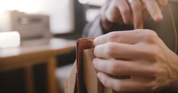 Крупним планом знімок чоловічих рук шиття шкіряної сумки ручної роботи на сідлі з голкою у виробничому майстерні стартового простору . — стокове відео