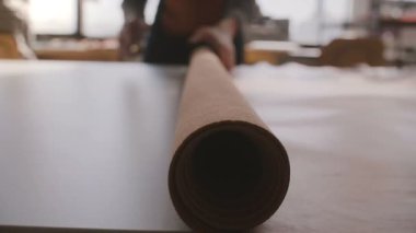 Yakın çekim görünümünü açma ve deri büyük bir rulo büyük atölye masada yayılan Profesyonel esnaf iş adamı.