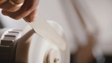 Güzel yakın çekim sabit taşlama makinesi disk aracı kullanarak eski bıçak bıçak bileme erkek işçi el vurdu.
