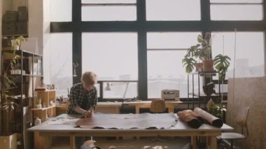 Adam craftswoman kesme deri el yapımı ürünler yapmak için bir tablosundaki nerede üretim Atölyesi içine yürüyüş önlük.
