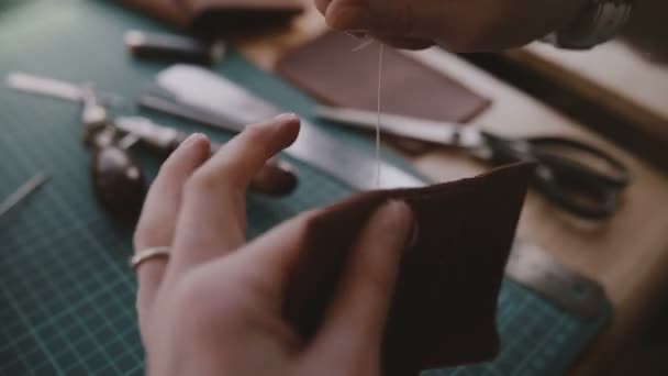 Close-up tiro de profissional artesanal empresária mãos costurando uma tampa de couro artesanal na mesa de ferramentas oficina moderna . — Vídeo de Stock