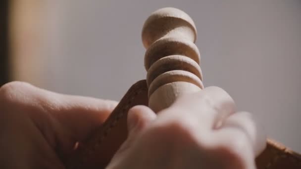 Close-up shot of professional male hands polishing handmade leather cover with special abrasive wooden finish stick. — Stock Video