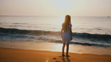 Arkadan Görünüm şaşırtıcı epik golden sunset beach adlı yaklaştığını mutlu heyecanlı küçük kadın çocuk izlerken okyanus dalga vurdu.