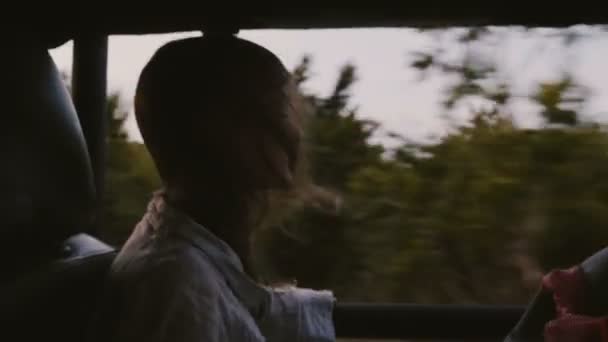 Glücklich kleines entspanntes lächelndes Touristenmädchen, das rückwärts im Safariauto reitet und bei einem Ausflug die Haare im Wind weht. — Stockvideo