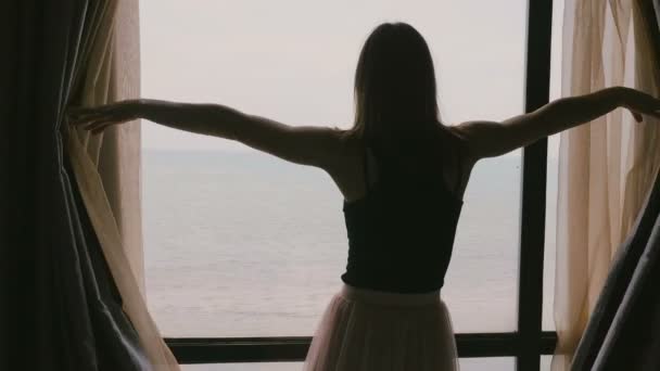 Młody szczęśliwy, zrelaksowany piękna kobieta otwiera okno zasłony w pokoju hotelowym, cieszyć się widokiem epickie ocean uśmiechający się w zwolnionym tempie. — Wideo stockowe