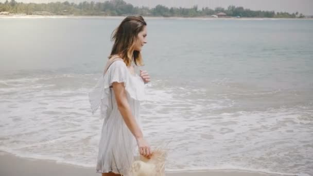 Young beautiful happy Caucasian woman walking along idyllic tropical ocean beach with calm waves relaxing and smiling. — Stock Video