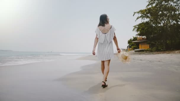 Vista trasera en cámara lenta feliz joven viajero atractivo mujer caminando lentamente en la playa exótica del océano tropical cámara lenta . — Vídeos de Stock