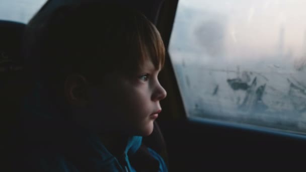 3-6 歳かわいい悲しい白人少年の暗い夜の中に霧の車の窓から外を見て映画のようなショットに乗る. — ストック動画