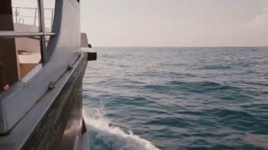 Kamera inanılmaz köpüklü beyaz dalgalar ile derin mavi deniz güneşli günde yelken yolculuk yat tekne sağ tarafında değil.