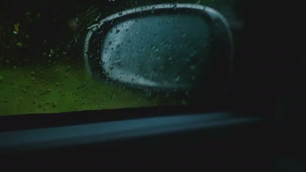 Filmový detail, rozostřeného boční zrcátko je vidět z jedoucího auta, zaměření na dešťové kapky na okně. — Stock video