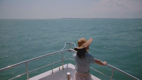 Wanita wisatawan muda yang bahagia memegang topinya dengan hidung kapal pesiar menikmati laut yang cerah dan berangin sempurna saat berlibur . — Stok Video