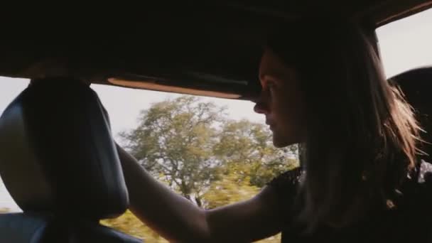 Junge glückliche Touristin lächelt, genießt schöne Fahrt im Safari-Ausflugsauto entlang des sonnigen wilden Waldes im Urlaub. — Stockvideo