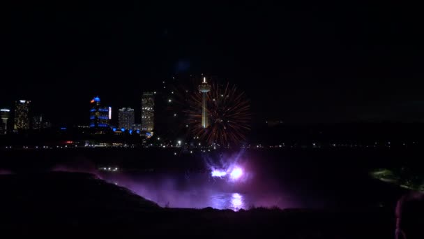 Niagarafälle 17. August 2018 schönes Feuerwerk, das über Nacht aufsteigt Wasserfall und beleuchtete Gebäude Zeitlupe. — Stockvideo