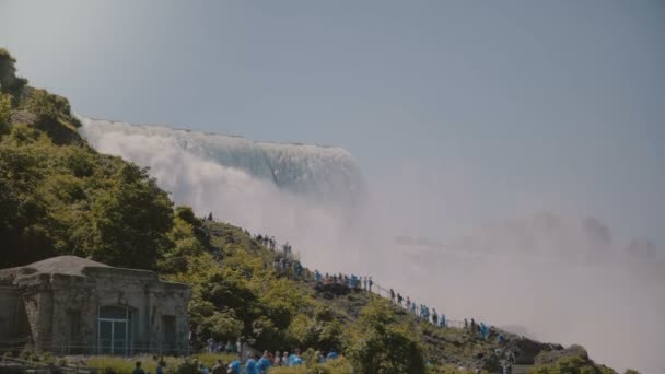 在阳光明媚的日子里, 身穿雨衣走上梯子的游客在史诗般美丽的尼亚加拉瀑布瀑布上拍摄了电影人的照片 — 图库视频影像