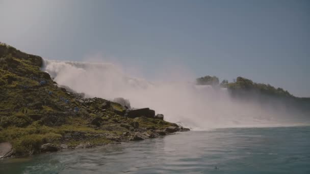 Filmische Aufnahme von Touristen in Regenmänteln, die an sonnigen Tagen epische Wasserwände am schönen berühmten Niagara-Wasserfall beobachten. — Stockvideo
