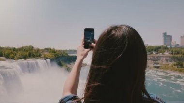 Muhteşem Niagara Şelalesi Panoraması fotoğraf çekerken mutlu genç turist kadının güzel yavaş hareket geri görünümü çekim