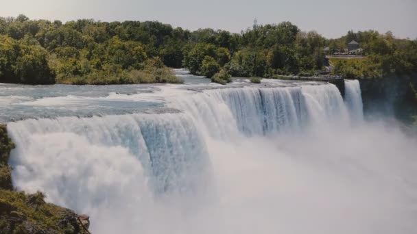 Hermoso paisaje de fondo de cámara lenta de la cascada épica de las Cataratas del Niágara que fluye hacia abajo con espuma en un día soleado de verano . — Vídeo de stock