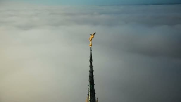 Drohne fliegt um goldene st michael-statue auf der spitze der festung mont saint michel turm glüht in der sonne über wolken — Stockvideo