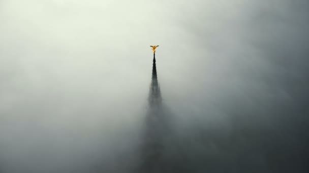 Drone acercándose a la estatua de oro épica en la parte superior de la famosa torre del castillo fortaleza Mont Saint Michel abadía cubierta por la niebla . — Vídeos de Stock
