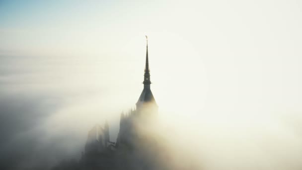 Dron volando sobre majestuosa estatua dorada en la cima de la torre del castillo de mont saint michel sobre nubes de sol en Normandía . — Vídeos de Stock