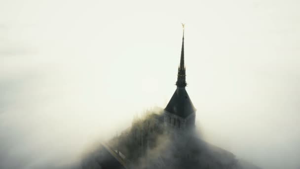 Drone vliegen rond prachtige zonnige gotische abdij gebouw op de top van de Mont Saint Michel eiland onder wolken in Normandië. — Stockvideo