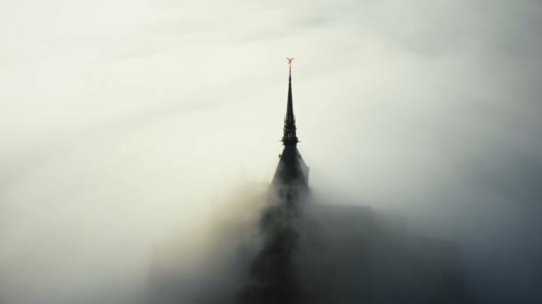 Plano aéreo de nubes de niebla del amanecer cubriendo misterioso castillo celestial de la fortaleza de mont saint michel en Normandía francia . — Vídeos de Stock