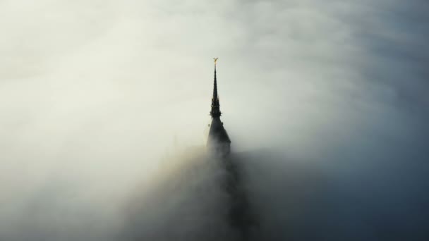 Asombrosa toma aérea de espesa niebla que cubre majestuosa torre del castillo fortaleza de mont saint michel al amanecer en Normandía Francia — Vídeo de stock