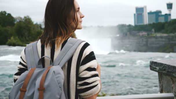 Visão traseira da mulher caucasiana local feliz com mochila olhando para a direita, assistindo cachoeira no Niagara Falls câmera lenta . — Vídeo de Stock