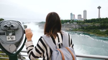 Epik Niagara Şelalesi yavaş hareket içinde sikke işletilen dürbün üzerinde tek elle mutlu turist kadının arkasında kamera slaytlar