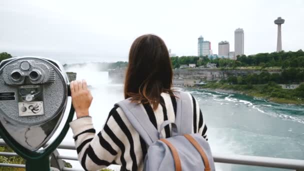 Kamera glider bakom lycklig turist kvinna med en hand på mynt som drivs kikare på episka Niagara vattenfall slow motion — Stockvideo