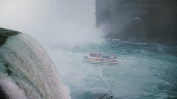 NIAGARA FALLS AUG 17 2018 Туристическая экскурсионная лодка находится недалеко от водопада, вода падает из замедленной съемки скалы . — стоковое видео