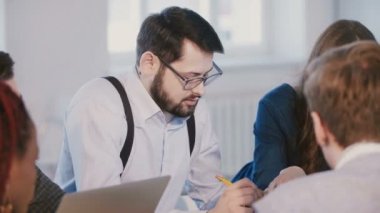 Genç başarılı Kafkas işadamı dinleme orta çekim portre, toplantı modern ofis masasının arkasında çalışıyor.