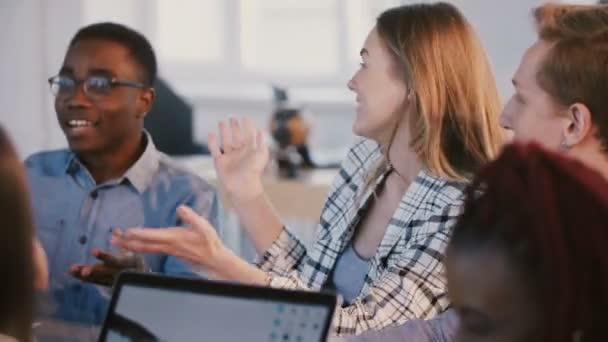 Medium shot van jong gelukkig multi-etnisch zakenpartners team praten, glimlachend op Brainstormen achter kantoor tafel. — Stockvideo