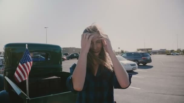 Portrait of young beautiful smiling American woman with flying hair posing at car park near cool old truck slow motion. — Stock Video