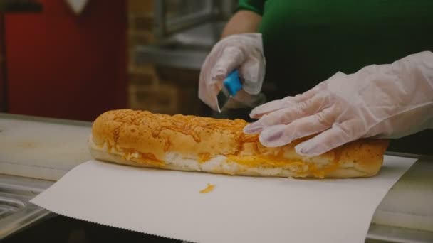 El proceso de hacer un gran sándwich de tamaño king, manos humanas obesas cortar gran pedazo de pan blanco por la mitad y poner en el horno — Vídeo de stock