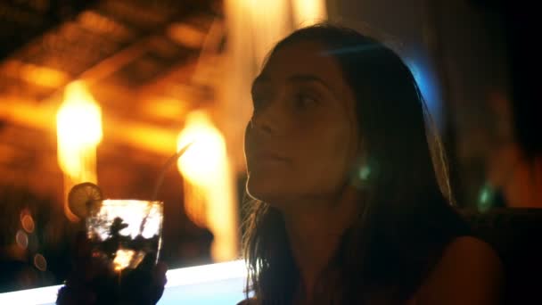 Щаслива розслаблена красива туристична жінка насолоджується коктейльним напоєм в атмосферному вечірньому пляжному барі з розмитими боке вогнями . — стокове відео