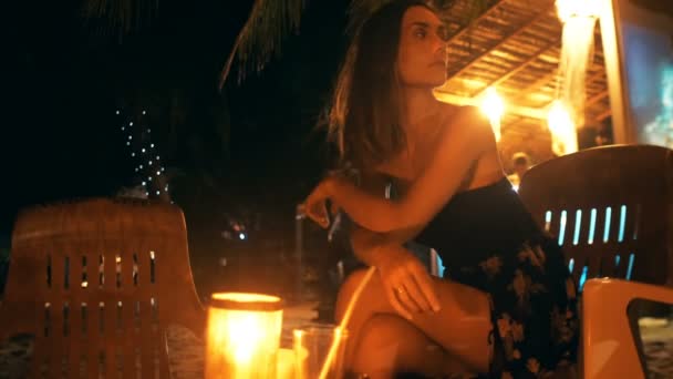 Piękna szczęśliwa kobieta turysta w nocy Beach Lounge Bar krzesło patrząc wokół czeka na kogoś na wakacjach Resort. — Wideo stockowe
