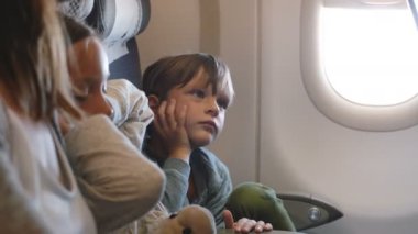 Sevimli küçük çocuk, görünümlü ve aile ile uzun tatil uçuşu sırasında uçak penceresi koltuk etrafında hareket sıkılmış.