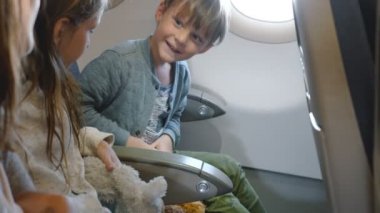 Aile ile tatile giden uçak uçuş sırasında mutlu küçük sevimli erkek ve kız bağlama emniyet kemeri yan görünümü.