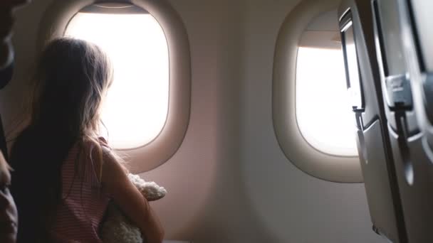 Beautiful background shot of happy little girl and boy enjoying view from airplane window seat during vacation trip. — Stock Video